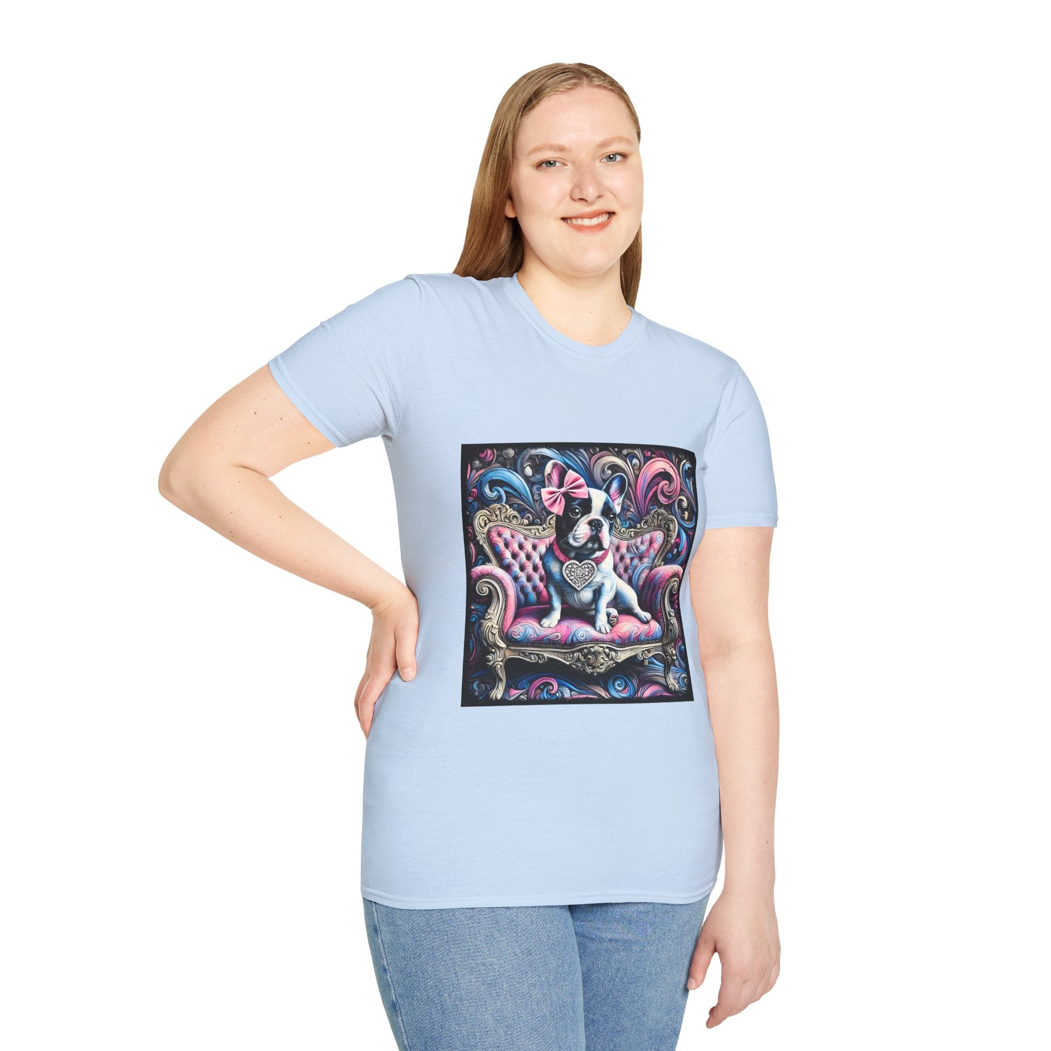 Female model in light blue dog t-shirt featuring a black and white French Bulldog with a pink bow, seated on a tufted pink and gold settee against a swirling blue, pink, and purple expressionist-style background.