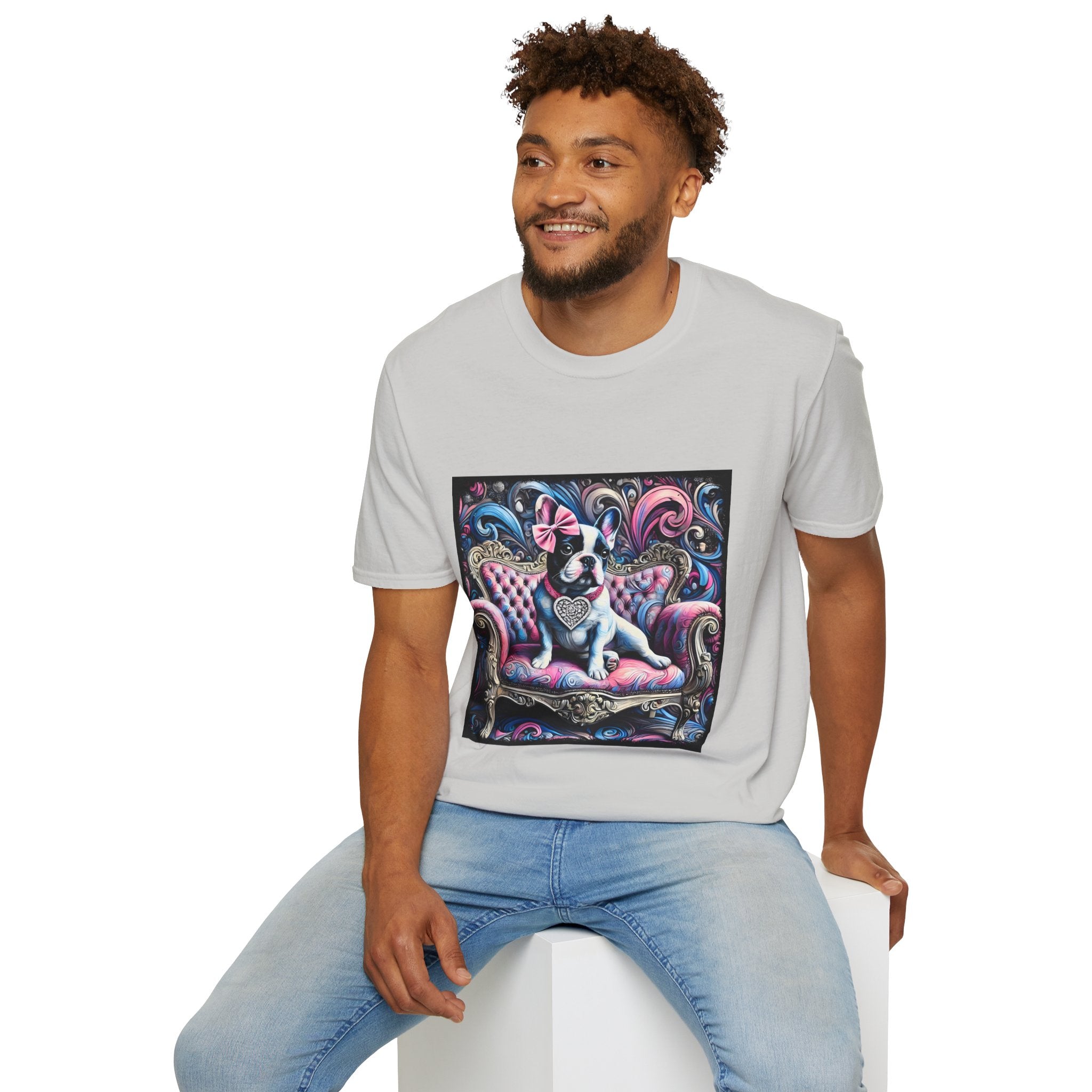 Male model in ice gray dog t-shirt featuring a black and white French Bulldog with a pink bow, seated on a tufted pink and gold settee against a swirling blue, pink, and purple expressionist-style background.