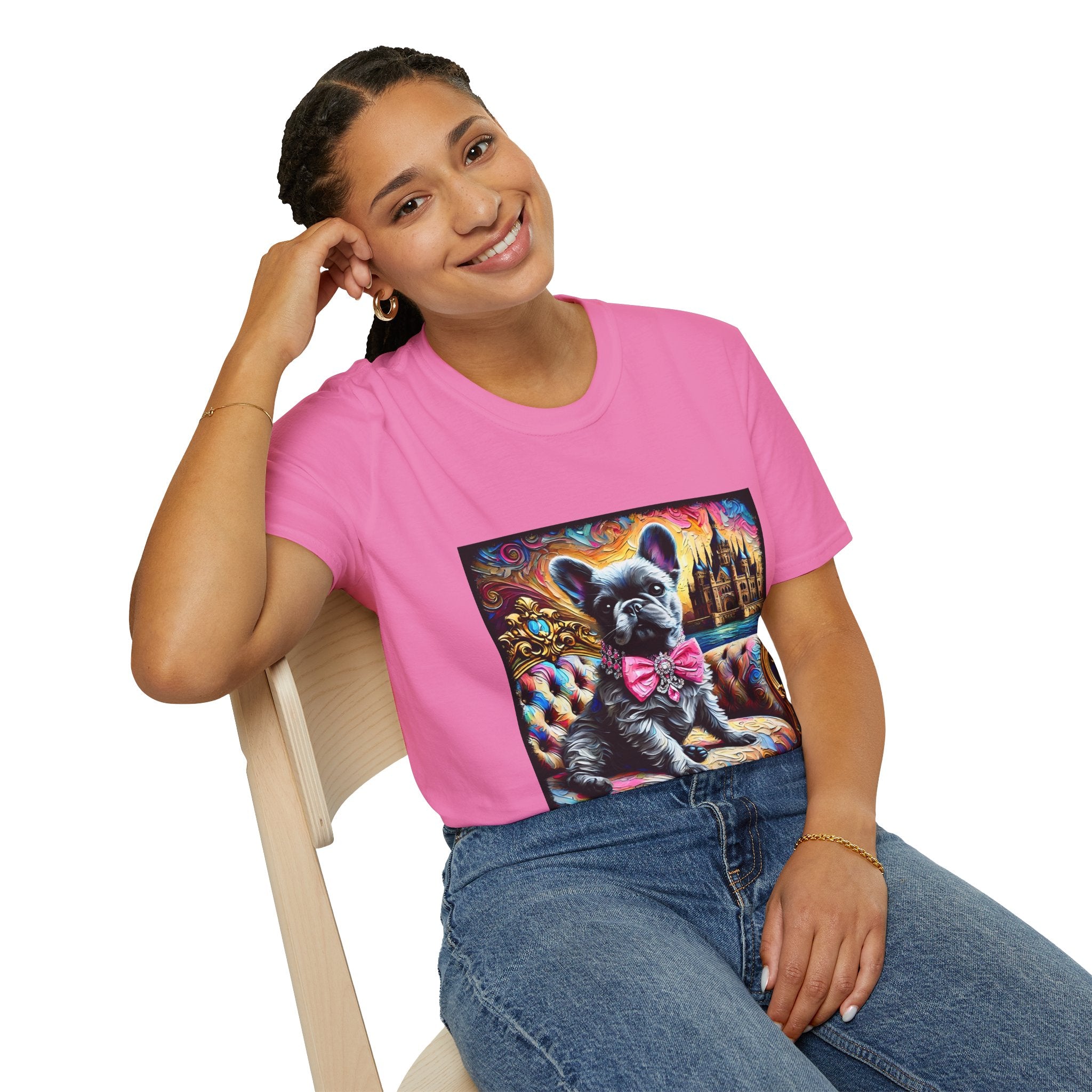 Smiling model wearing dark pink dog t-shirt featuring black French Bulldog in pink bow on ornate settee with colorful castle swirl background.