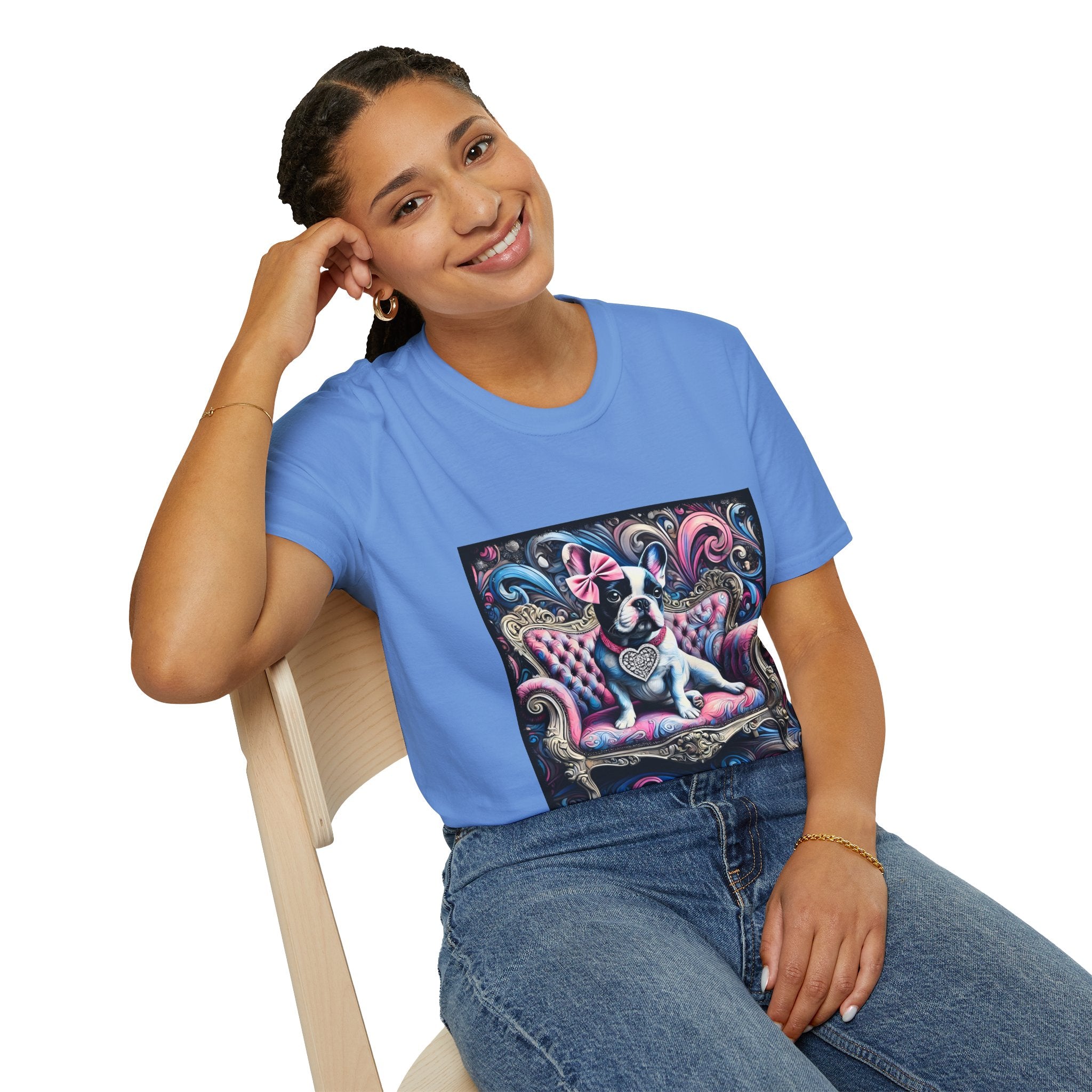 Female model in Carolina blue dog t-shirt featuring a black and white French Bulldog with a pink bow, seated on a tufted pink and gold settee against a swirling blue, pink, and purple expressionist-style background.