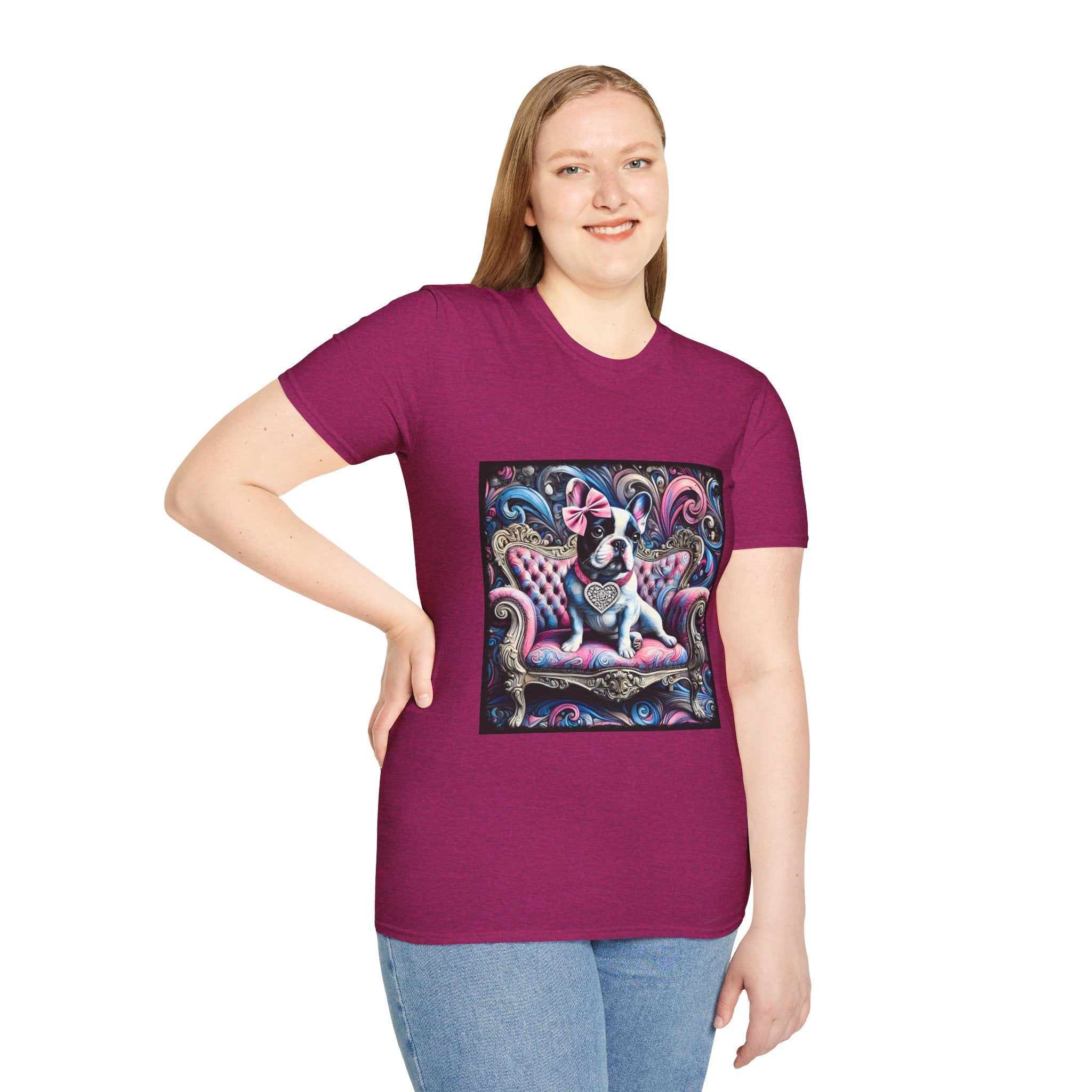 Female model in heather berry dog t-shirt featuring a black and white French Bulldog with a pink bow, seated on a tufted pink and gold settee against a swirling blue, pink, and purple expressionist-style background.