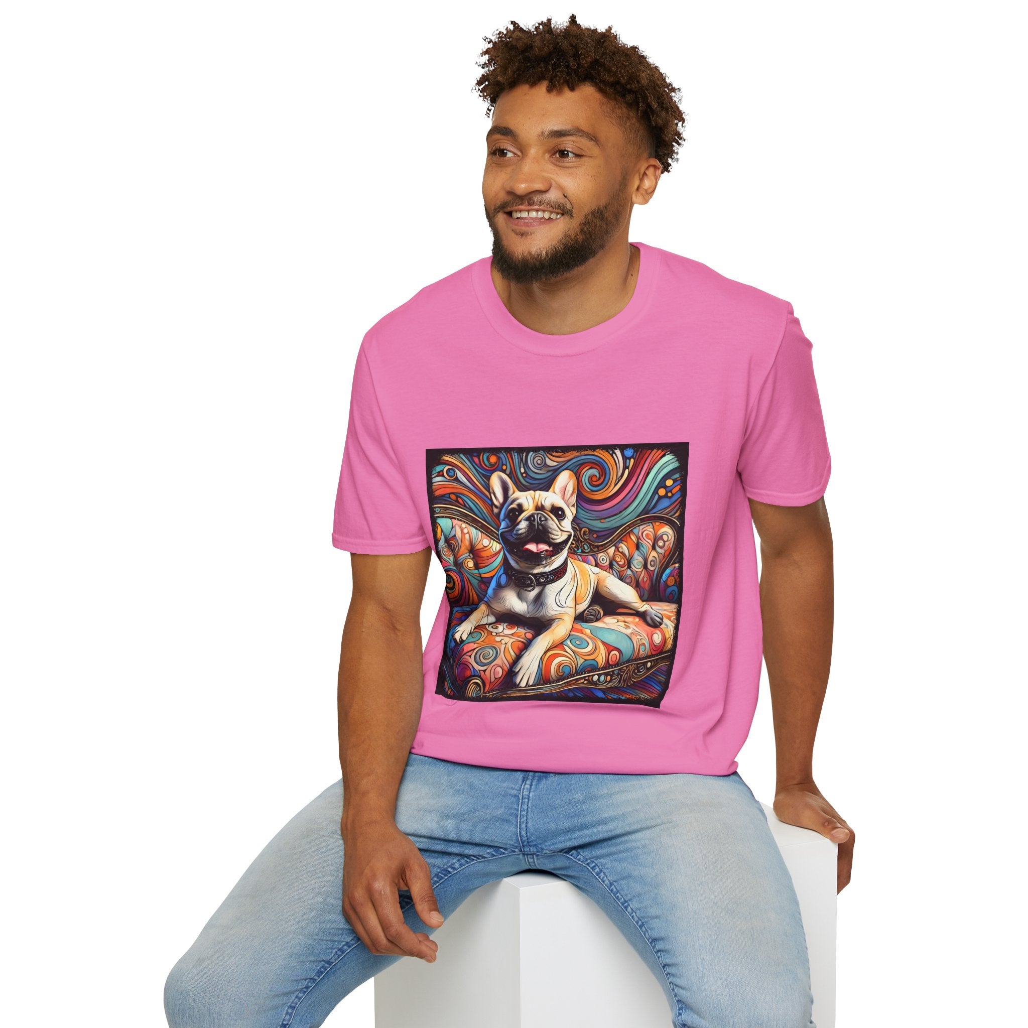 Male model in pink dog t-shirt featuring fawn French Bulldog with collar on swirl settee and vivid background.