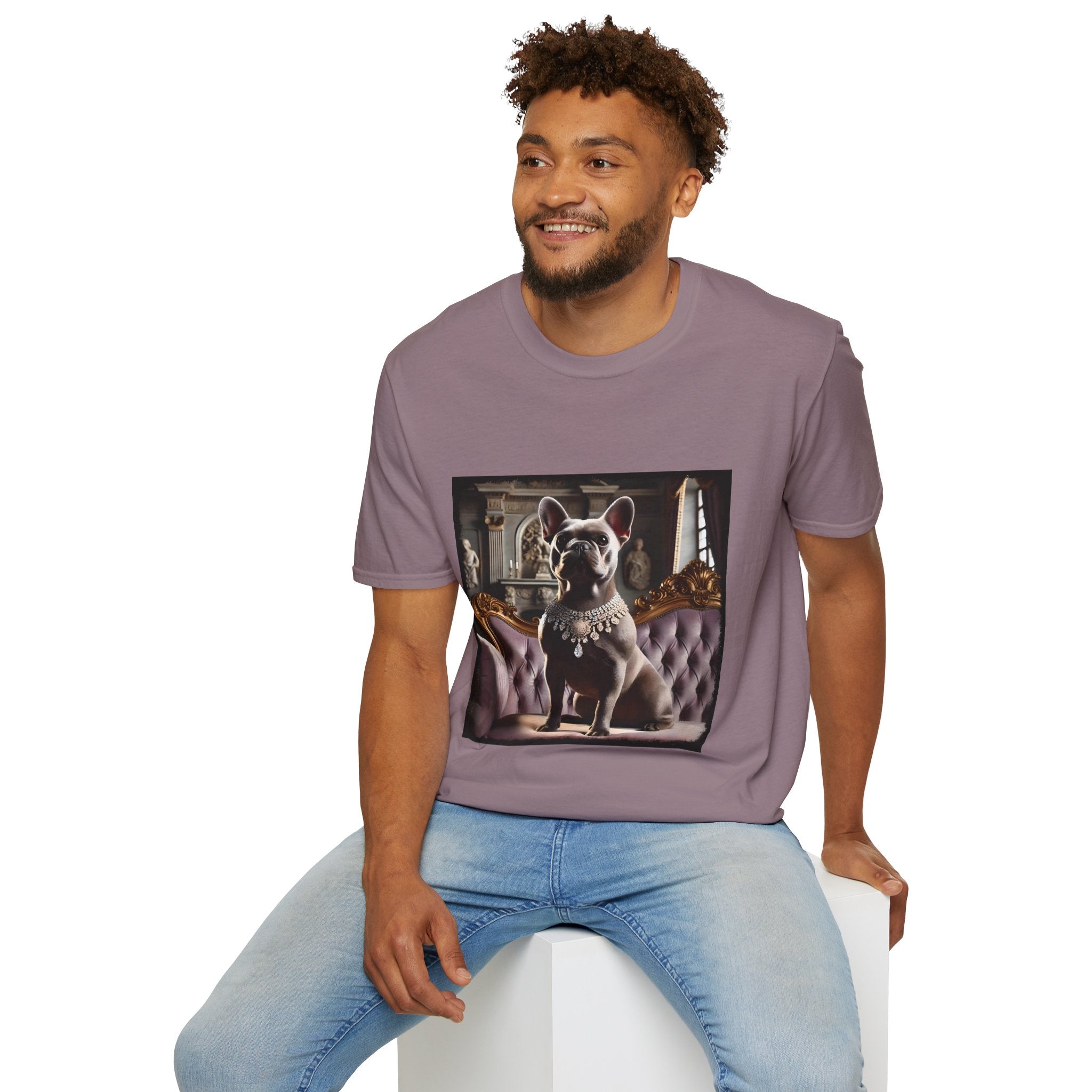 Male model in mauve dog t-shirt featuring gray French Bulldog in jeweled necklace on tufted settee in palace setting.
